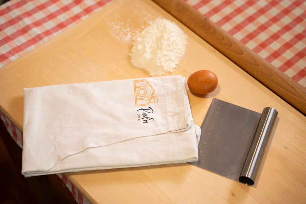Il canovaccio Paola Kitchen con farina, uovo, spatola e matterello: gli strumenti del corso