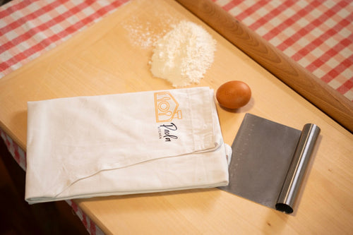 Il canovaccio Paola Kitchen con farina, uovo, spatola e matterello: gli strumenti del corso