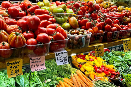 Pomodori, peperoni e carote su un banco di frutta e verdura del mercato di Bologna